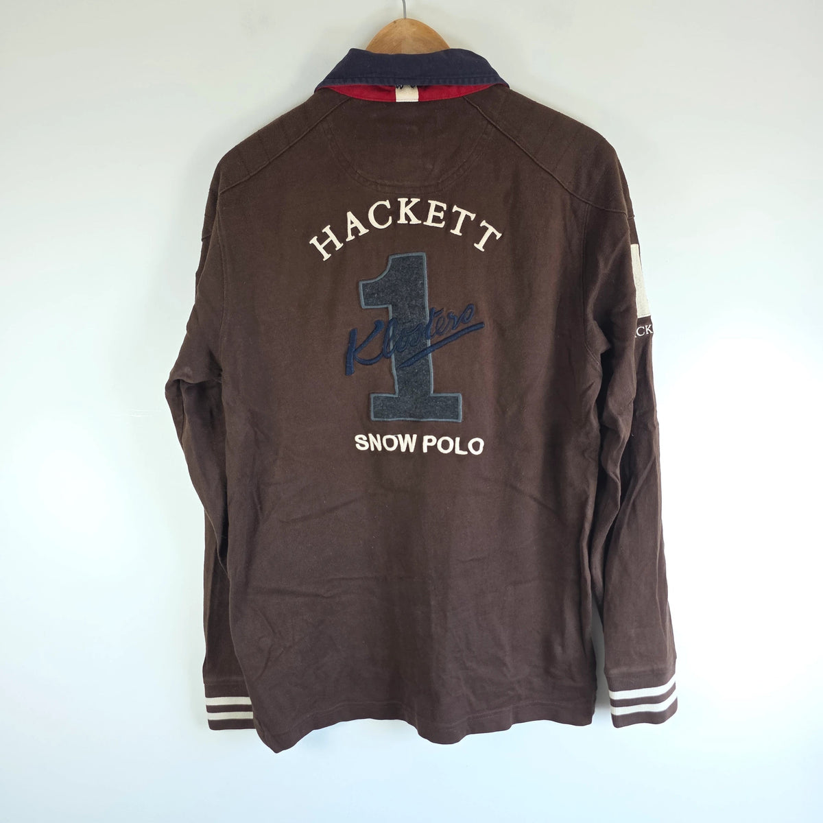 Hackett brown rugby polo shirt with navy collar, embroidered patches, and large back design.