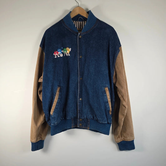M&M's blue denim varsity bomber jacket with embroidered characters and tan sleeves.