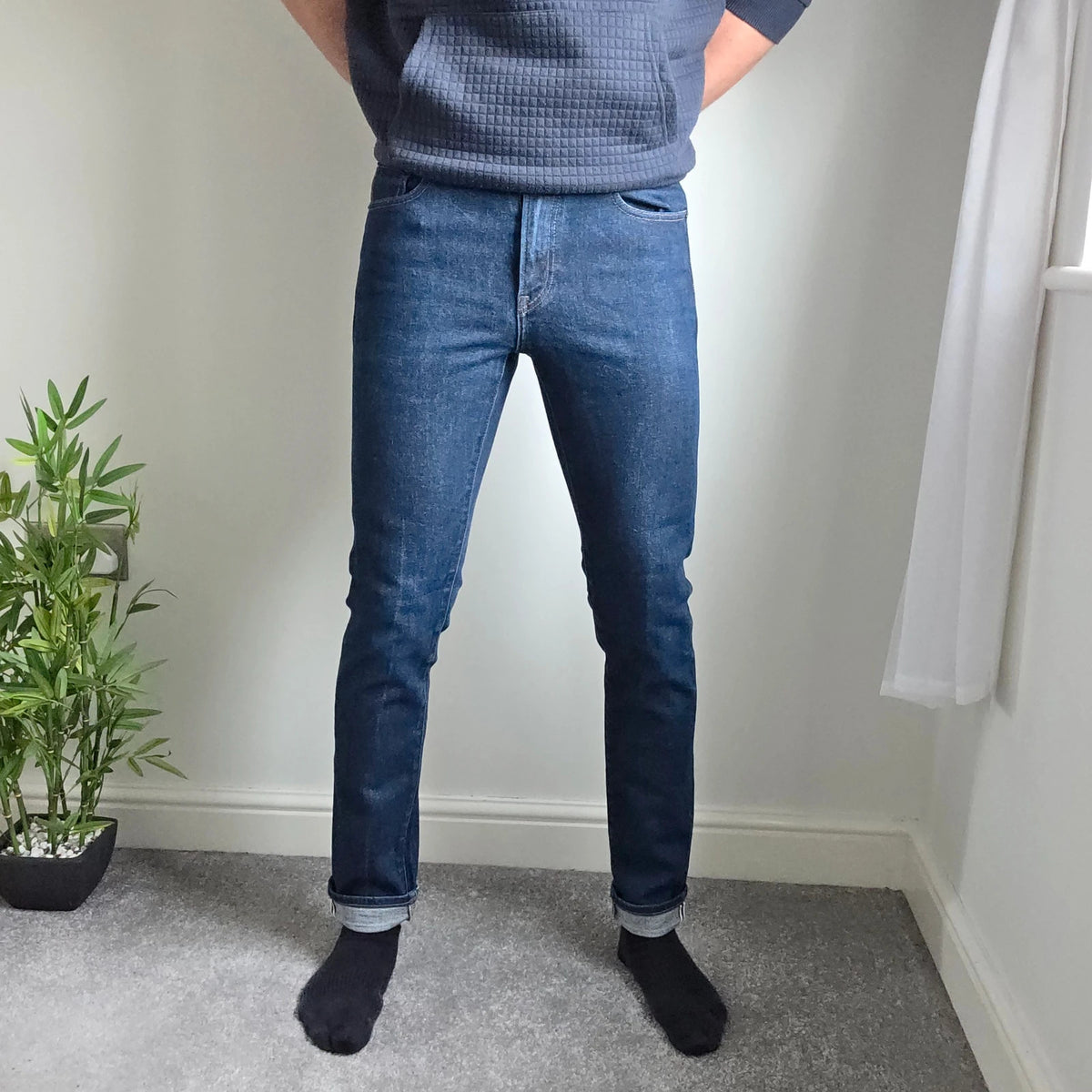 UNIQLO dark indigo slim straight jeans with selvedge detailing and stretch denim material.