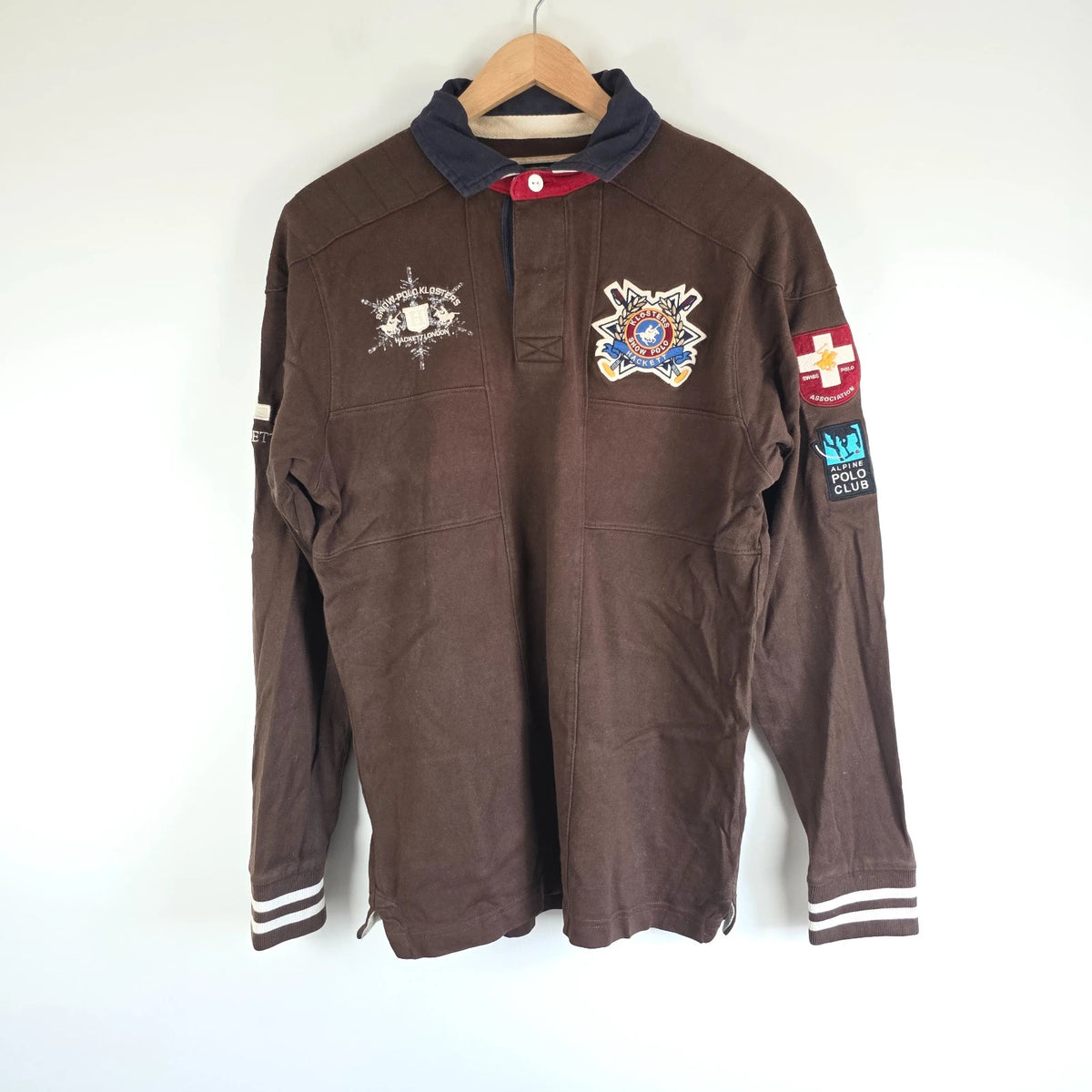 Hackett brown rugby polo shirt with navy collar, embroidered patches, and large back design.