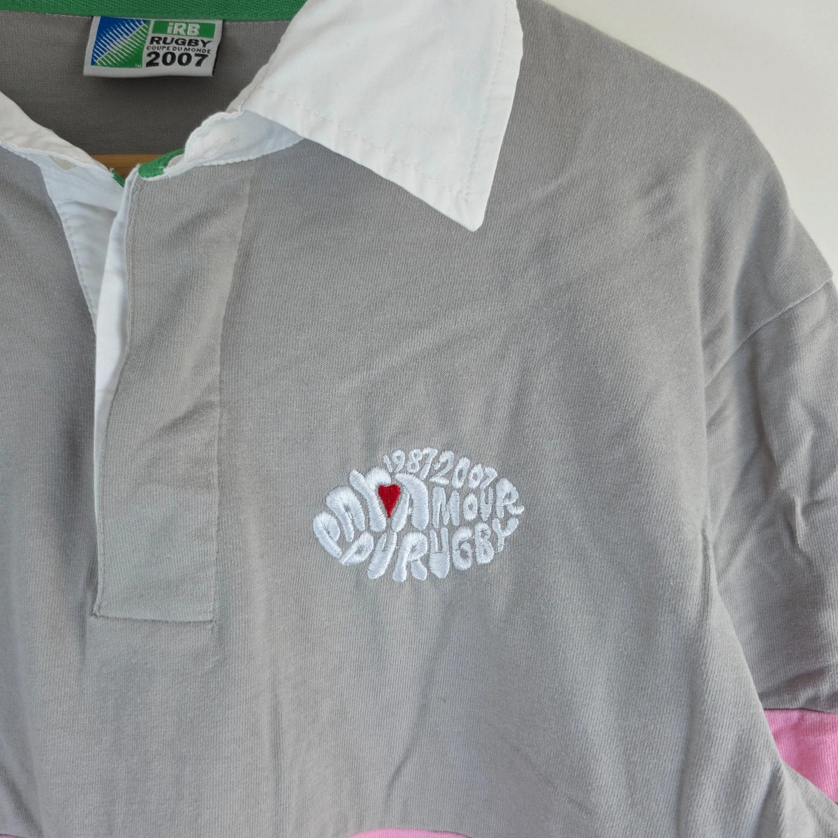 Rugby World Cup grey pink long sleeve polo shirt with IRB logo and Stade de France detail.