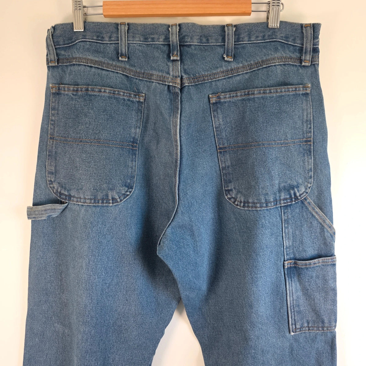 Rustler blue carpenter jeans with utility pockets and hammer loop detailing.