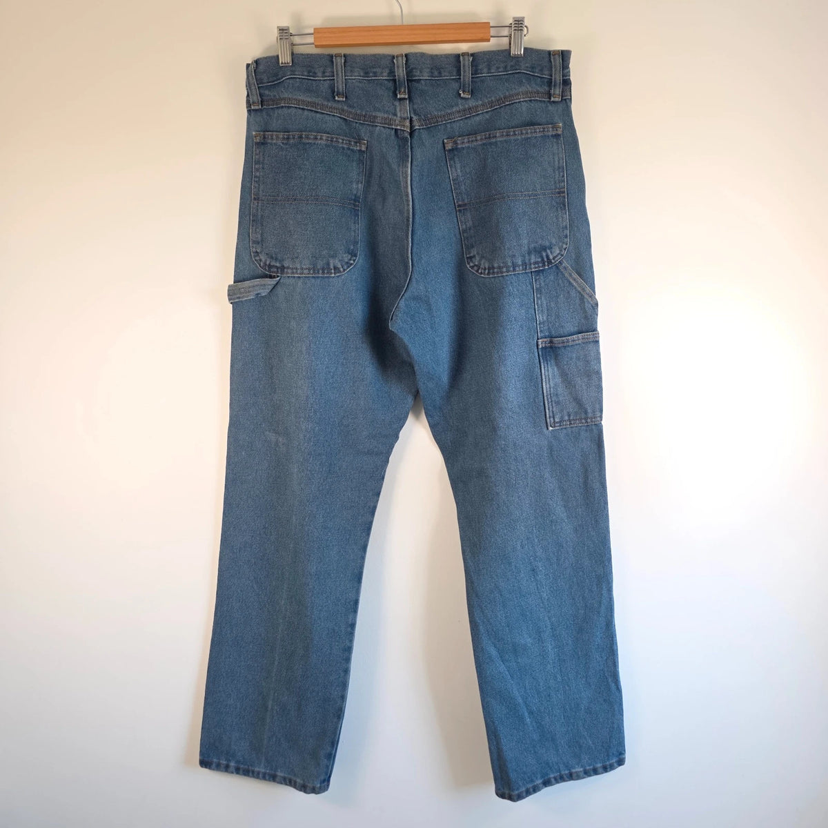 Rustler blue carpenter jeans with utility pockets and hammer loop detailing.