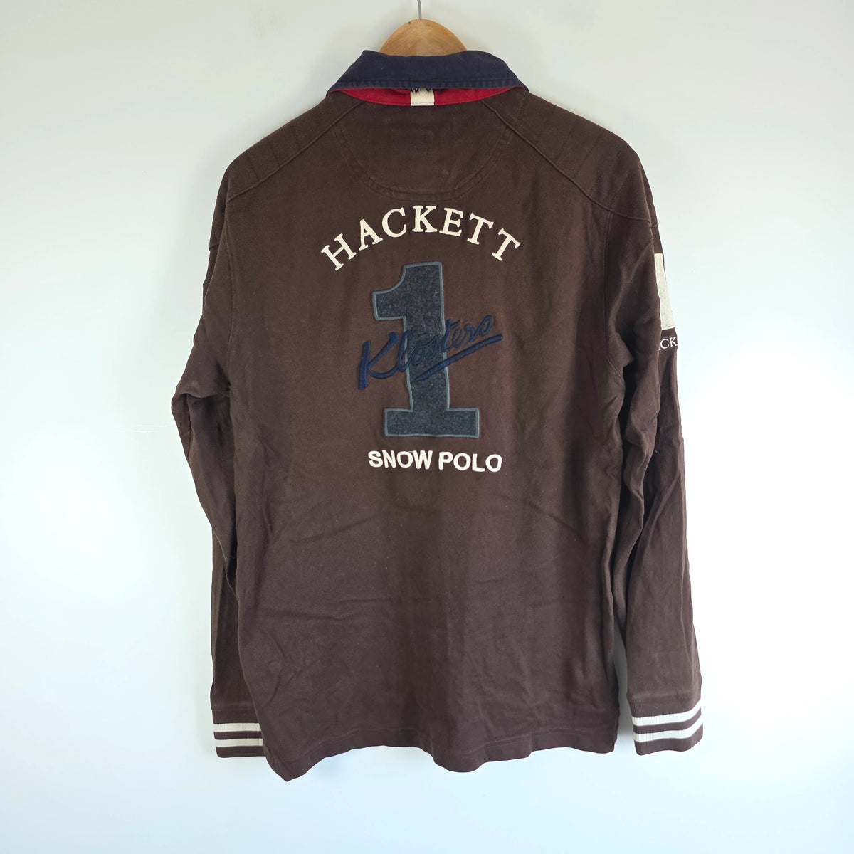 Hackett brown rugby polo shirt with navy collar, embroidered patches, and large back design.