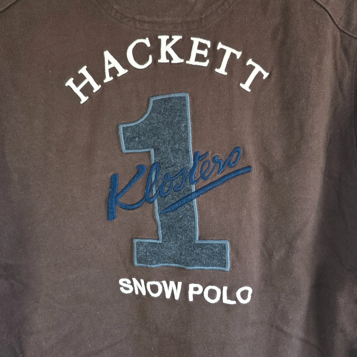 Hackett brown rugby polo shirt with navy collar, embroidered patches, and large back design.
