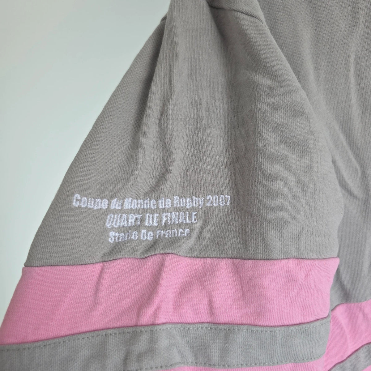 Rugby World Cup grey pink long sleeve polo shirt with IRB logo and Stade de France detail.