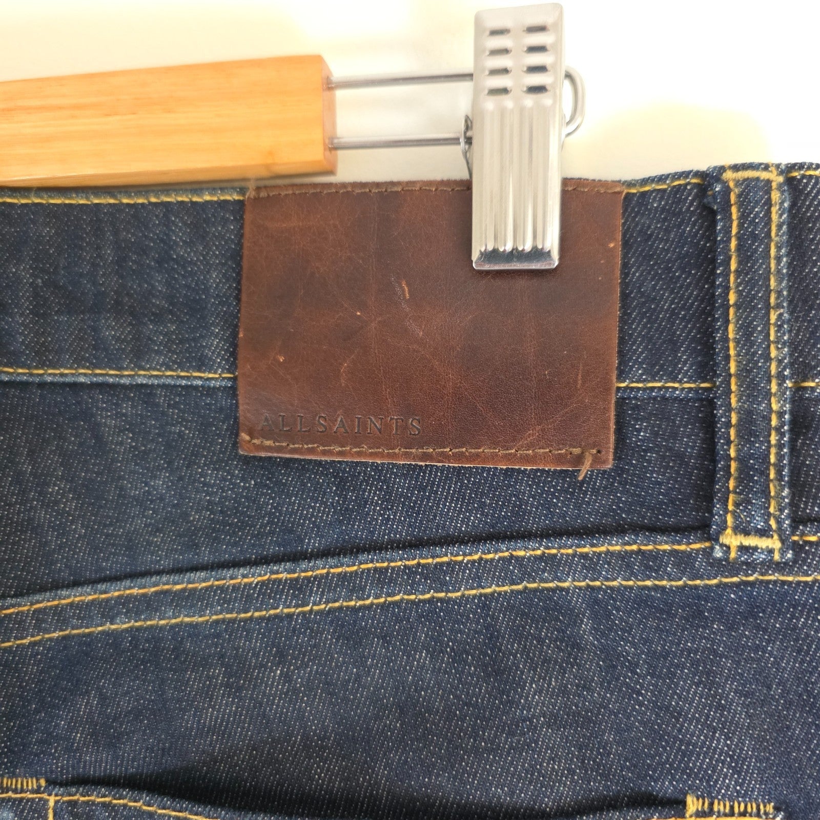 AllSaints blue skinny jeans with button fly and subtle logo detail.