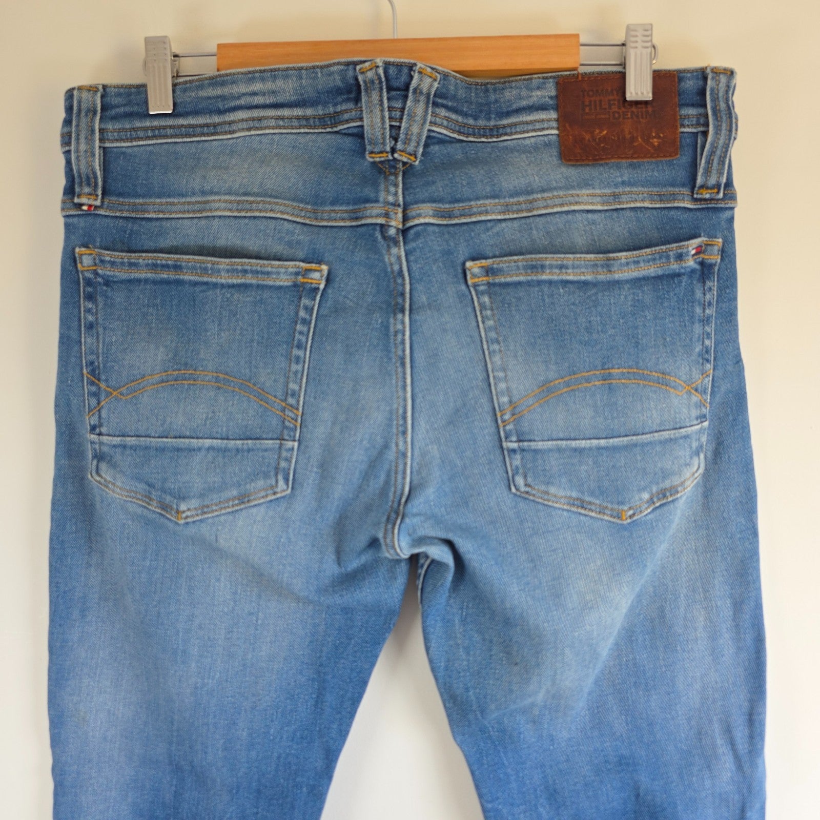 Tommy Hilfiger blue tapered jeans with stretch denim and small rip detail.