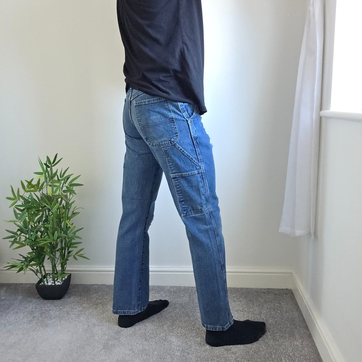 Wrangler blue carpenter jeans with distressed detailing, utility pockets, and hammer loop.