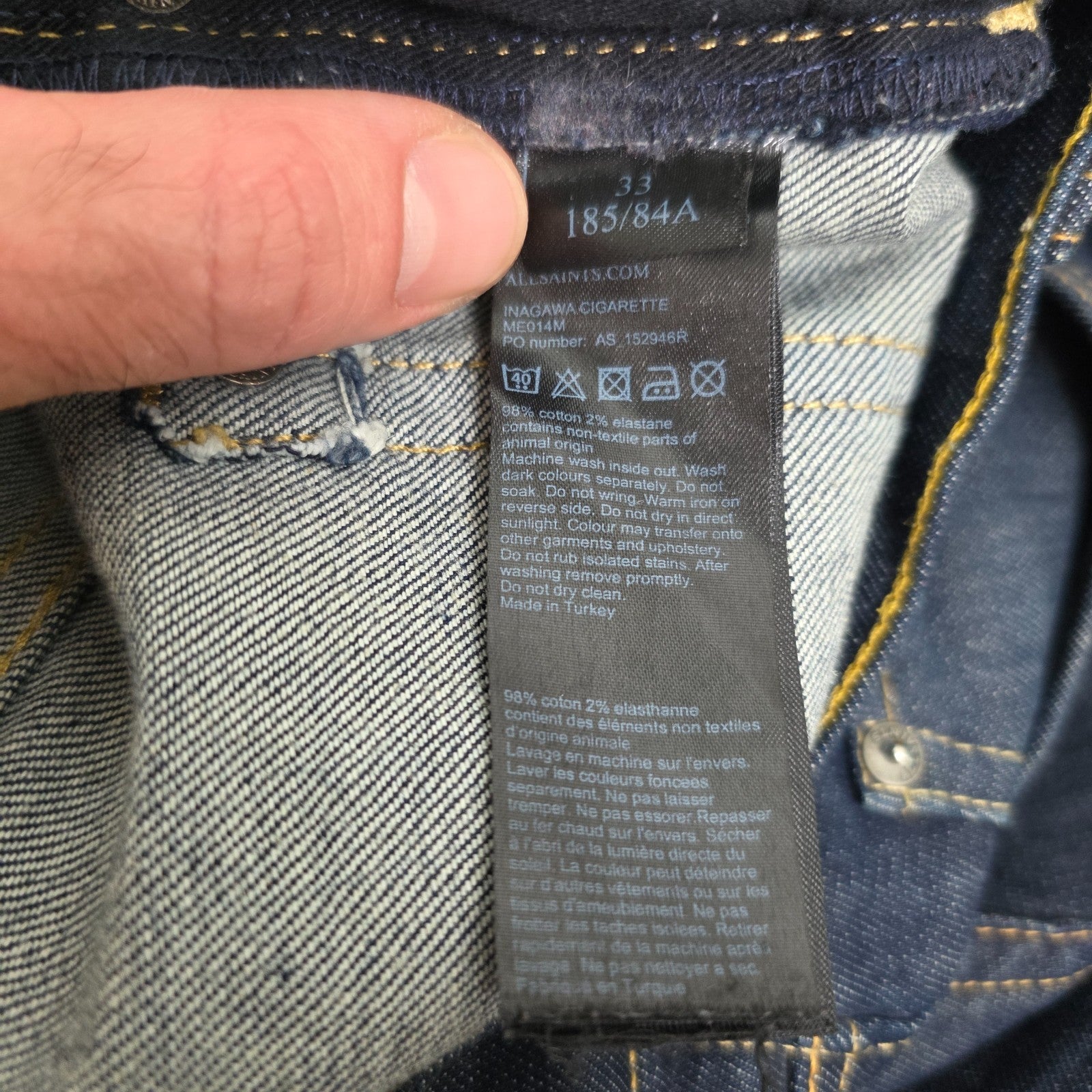 AllSaints blue skinny jeans with button fly and subtle logo detail.