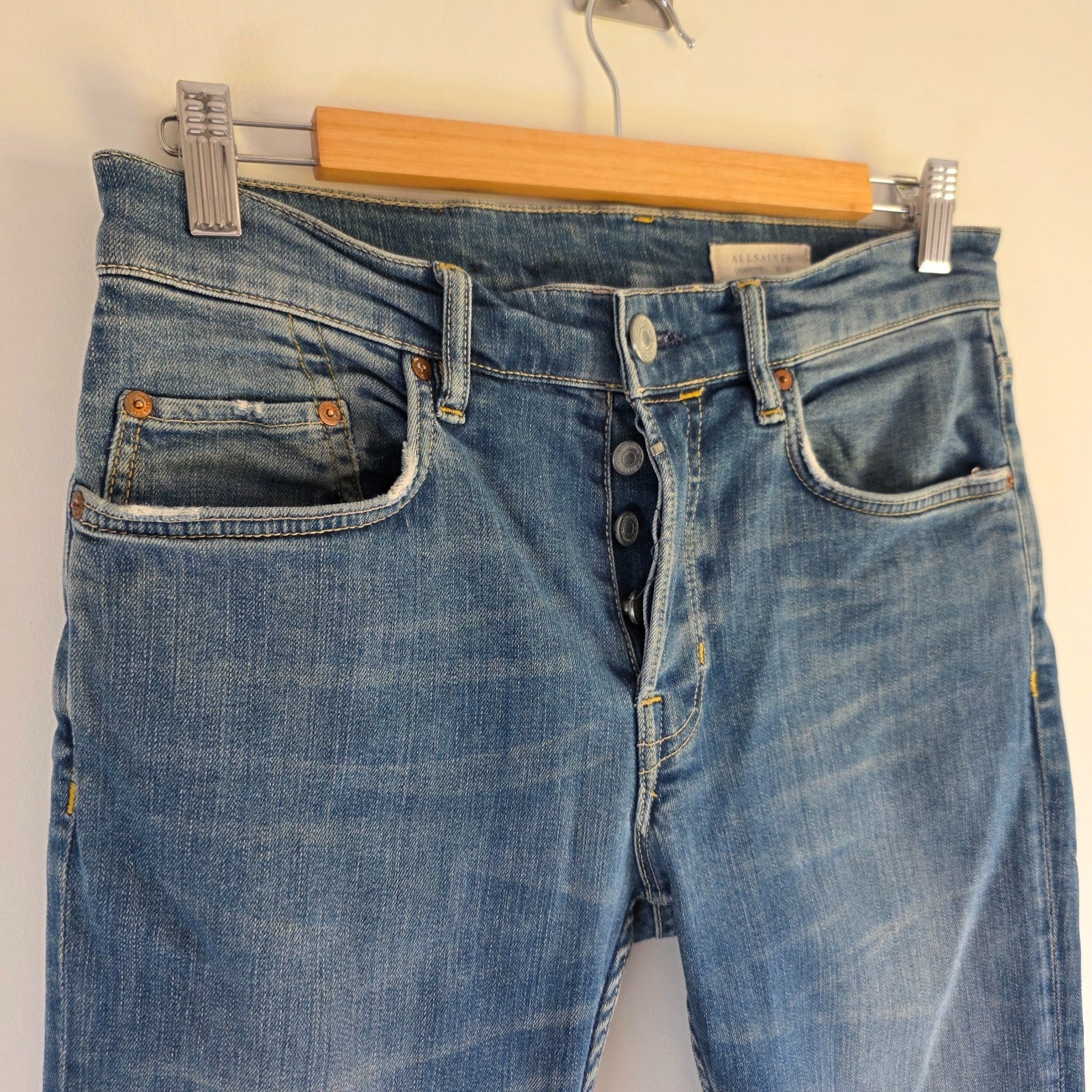 AllSaints blue skinny jeans with faded wash and modern slim fit design.