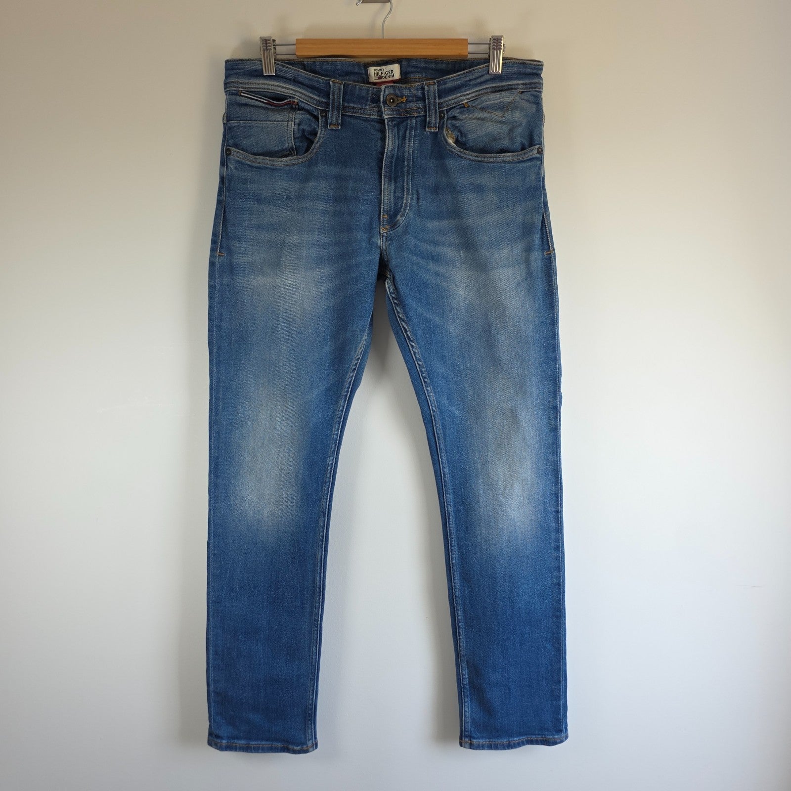 Tommy Hilfiger blue tapered jeans with stretch denim and small rip detail.