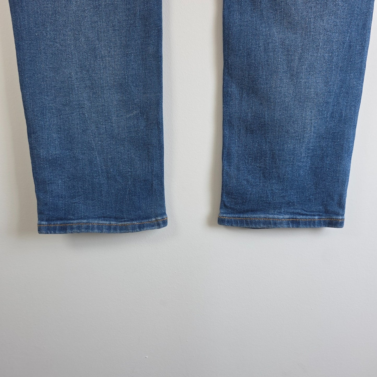 Tommy Hilfiger blue tapered jeans with stretch denim and small rip detail.