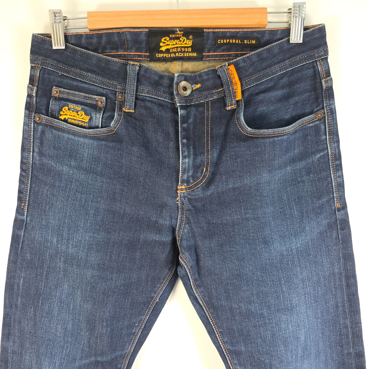 Superdry blue slim jeans with subtle fading, contrast orange stitching, and five-pocket design.