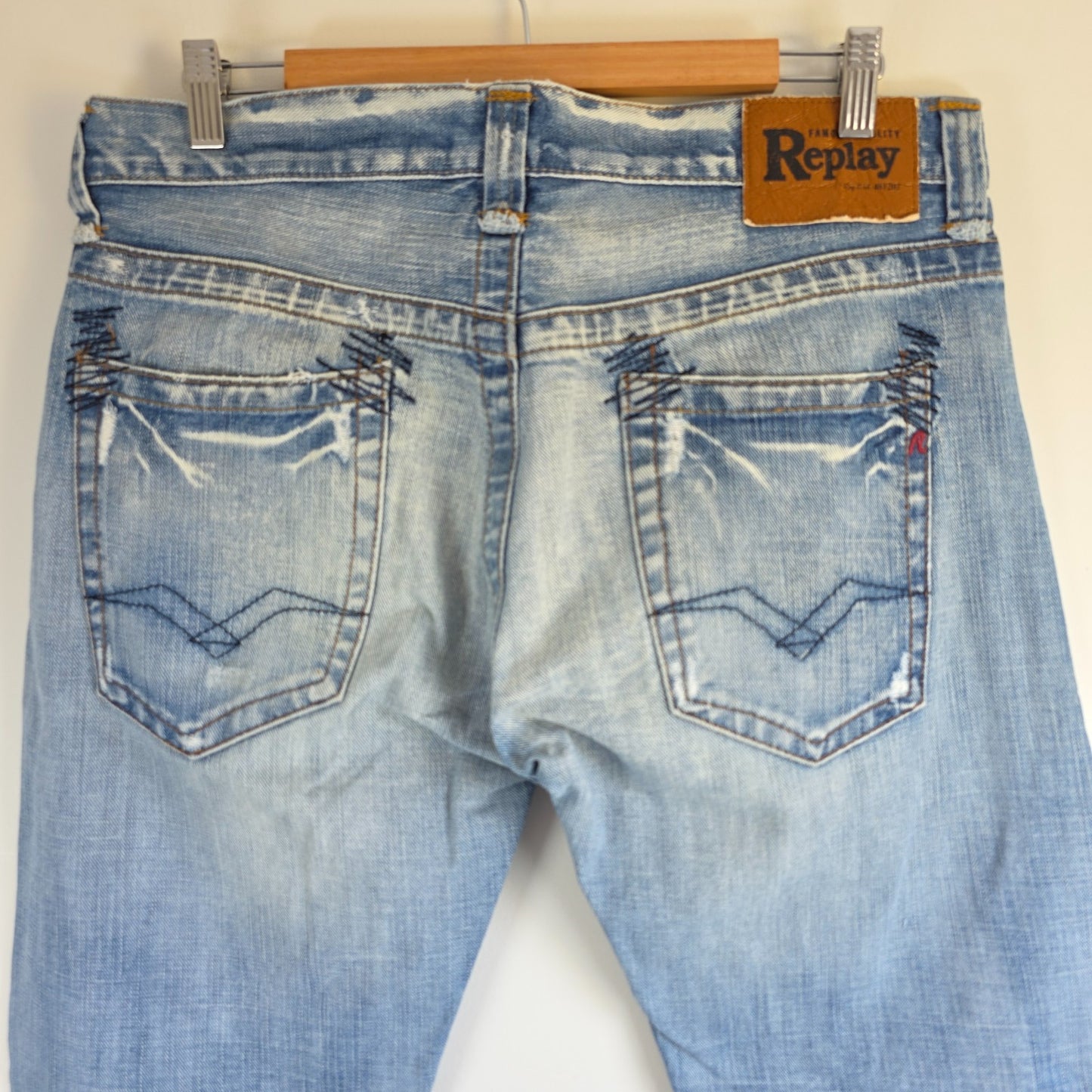 Replay blue straight jeans with button fly and light distressed pocket detailing.