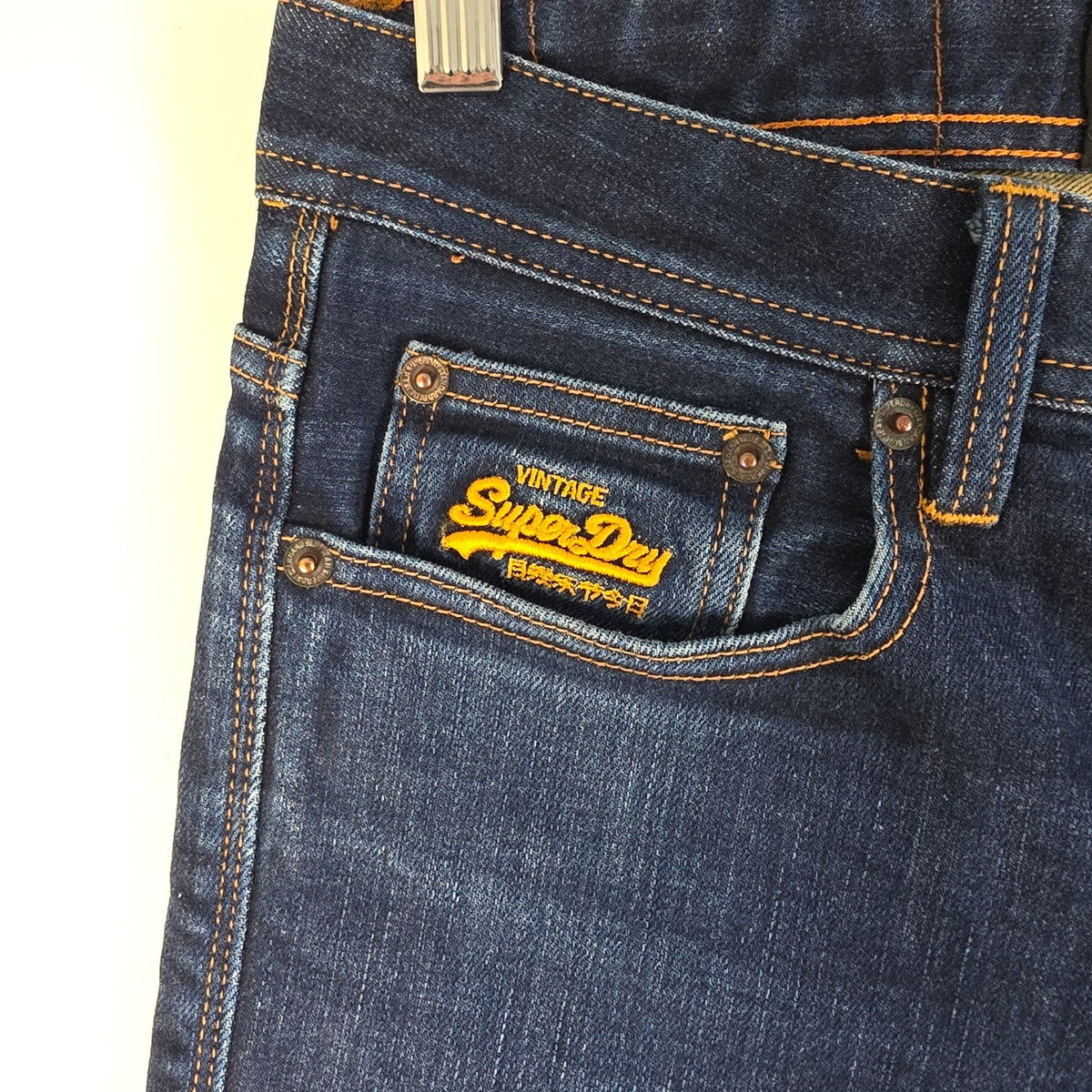 Superdry blue slim jeans with subtle fading, contrast orange stitching, and five-pocket design.