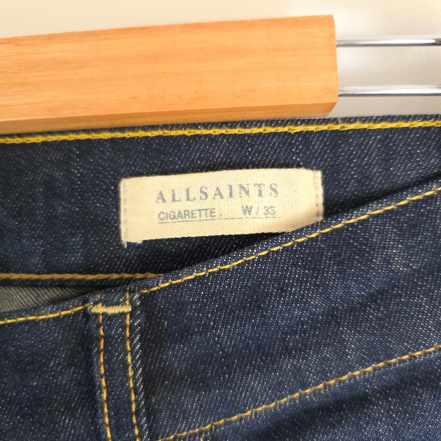 AllSaints blue skinny jeans with button fly and subtle logo detail.