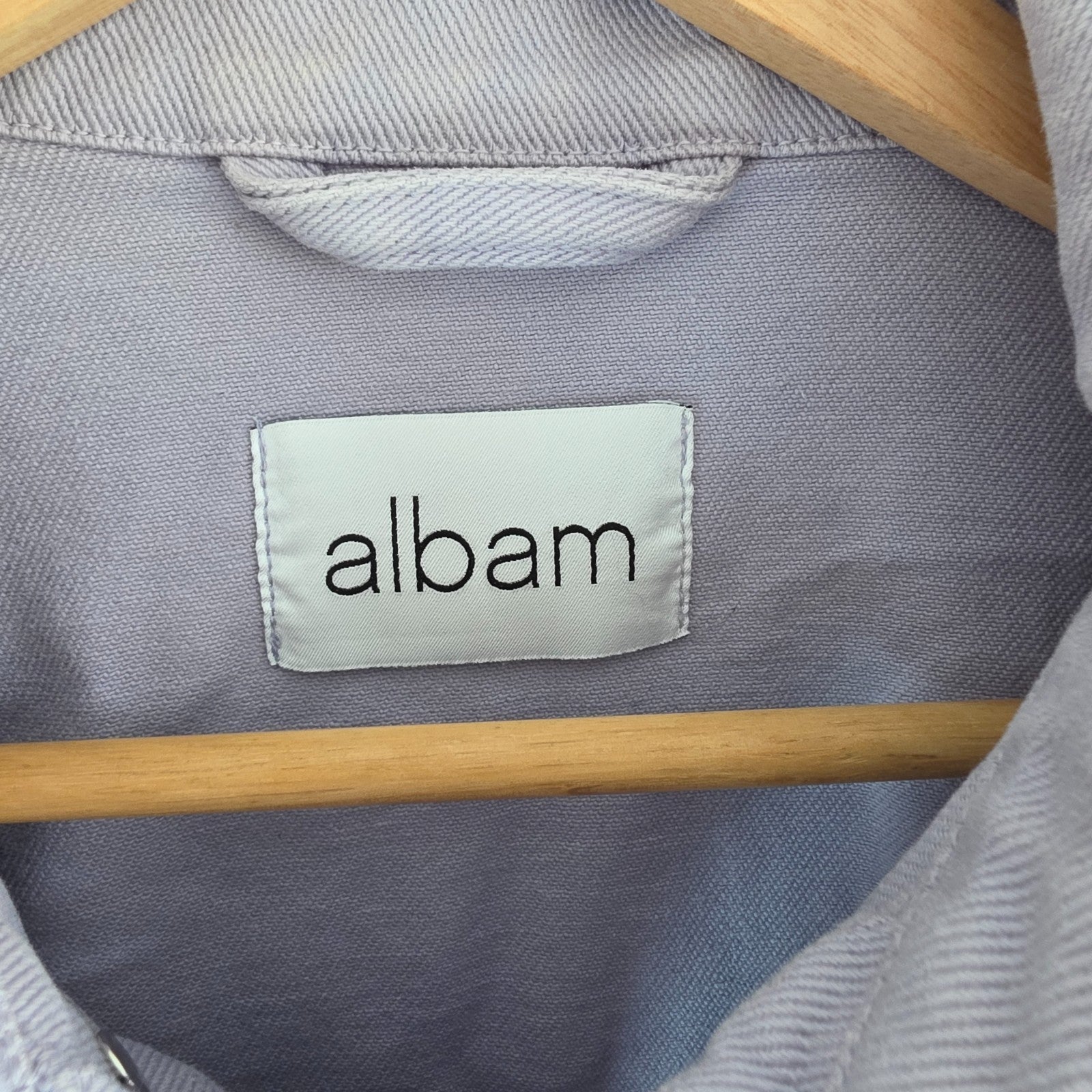 Albam lilac denim jacket with button front, chest pockets, and side pockets.
