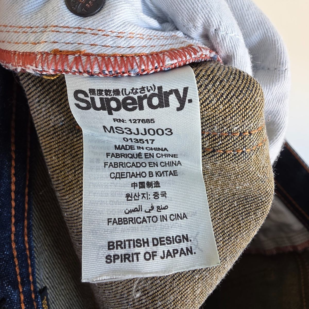 Superdry blue slim jeans with subtle fading, contrast orange stitching, and five-pocket design.