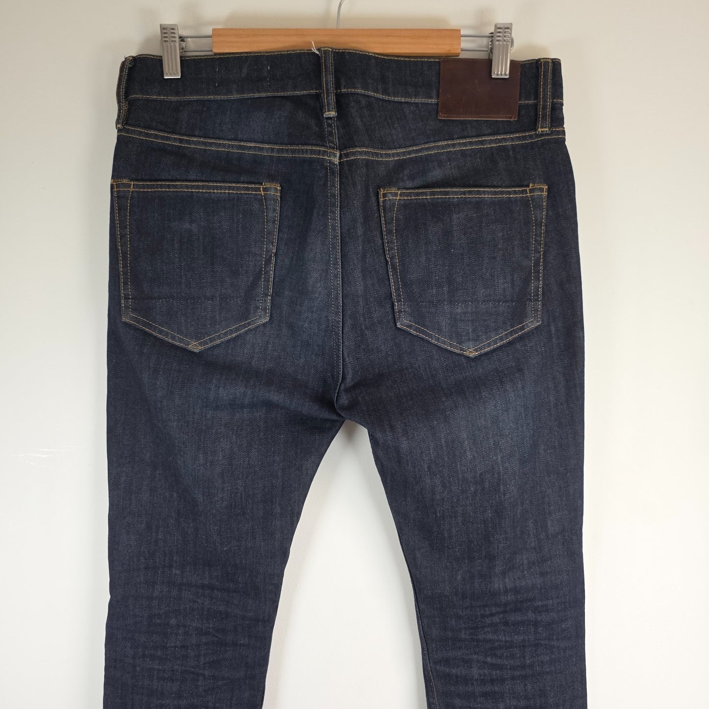 AllSaints blue skinny jeans with button fly and subtle logo detail.