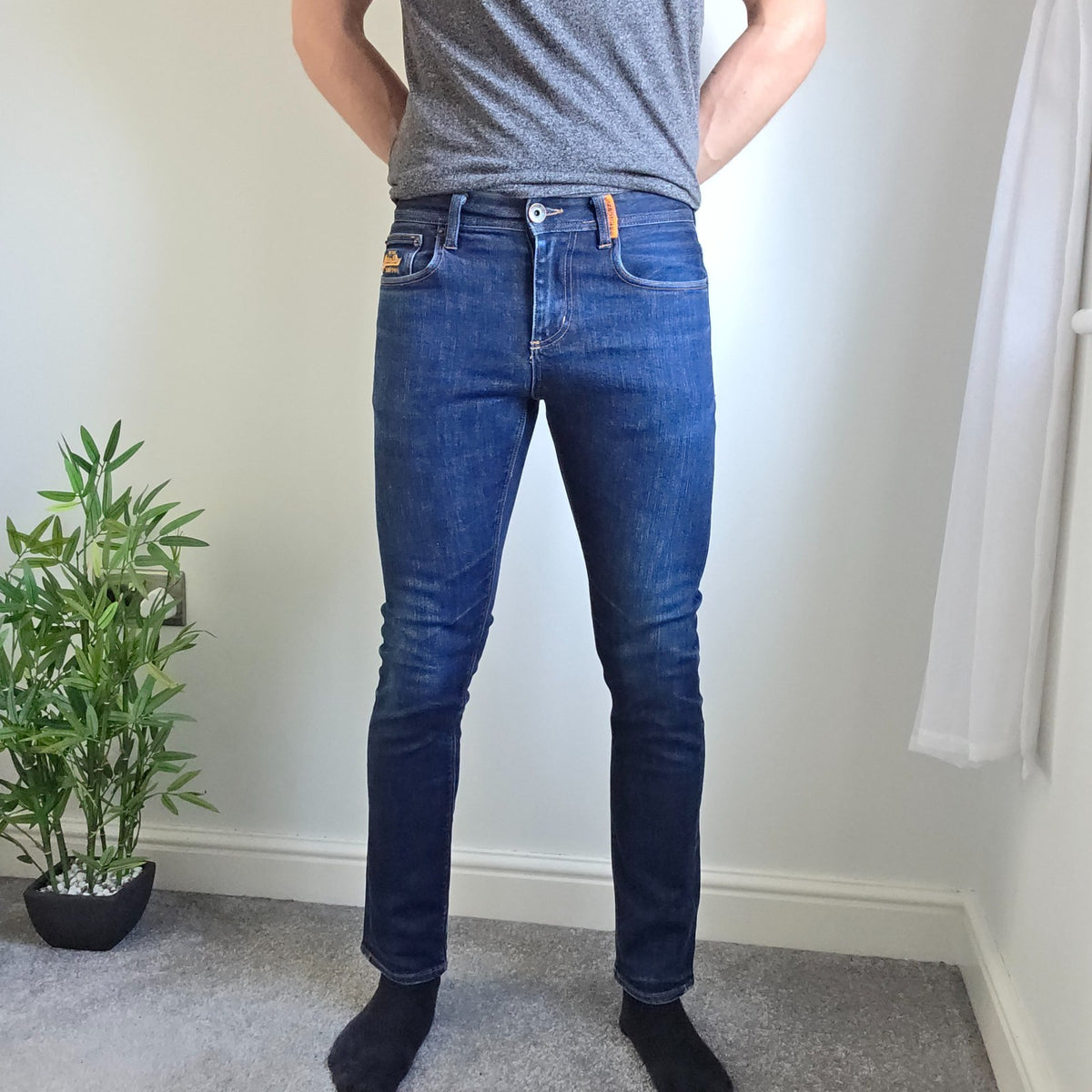 Superdry blue slim jeans with subtle fading, contrast orange stitching, and five-pocket design.