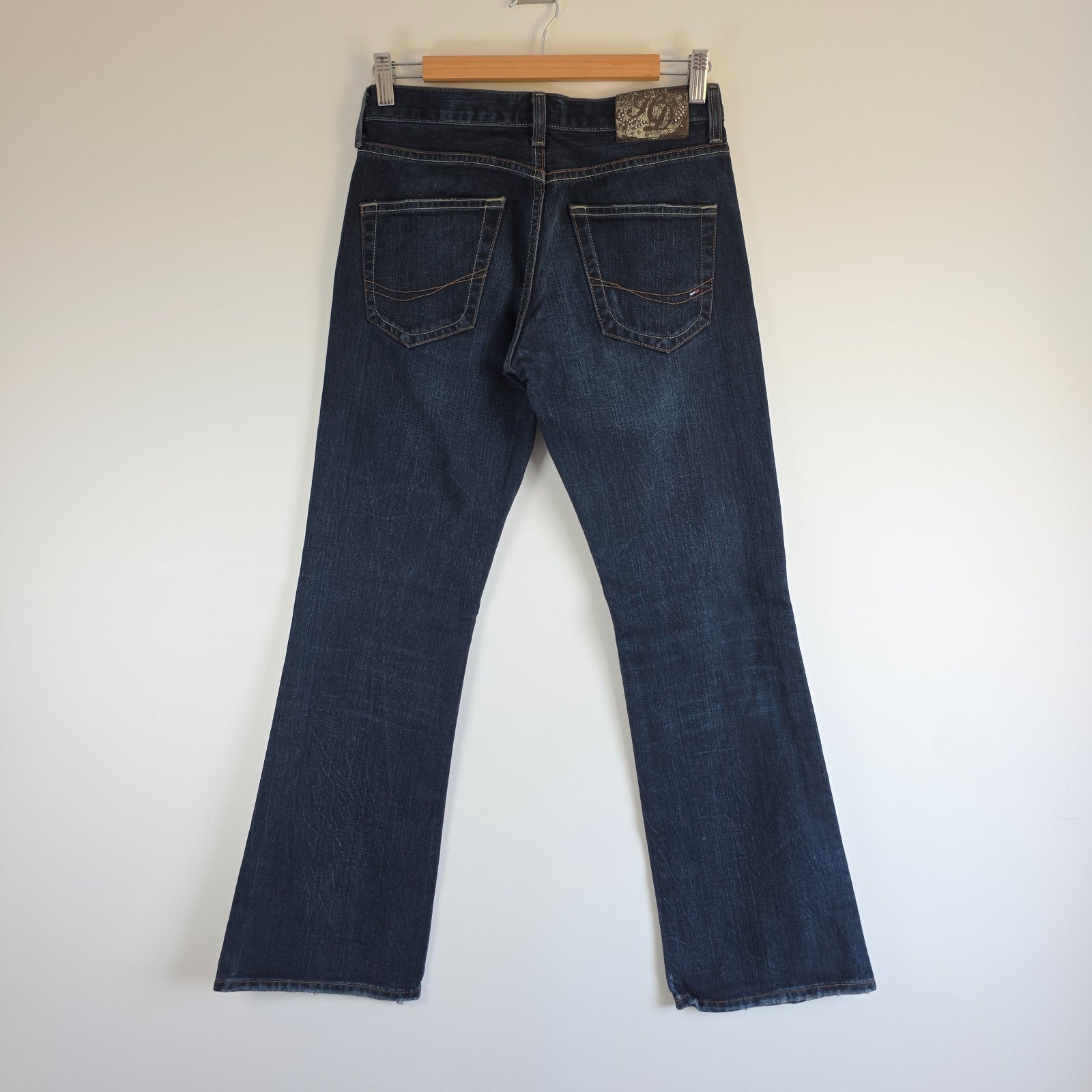 Tommy Hilfiger blue bootcut jeans with logo patch and classic denim texture.