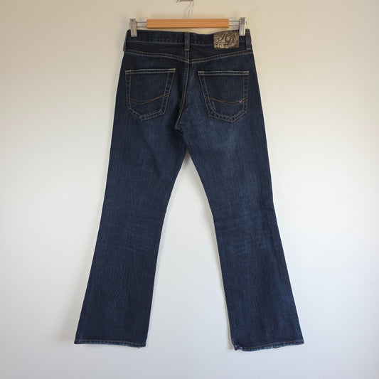 Tommy Hilfiger blue bootcut jeans with logo patch and classic denim texture.