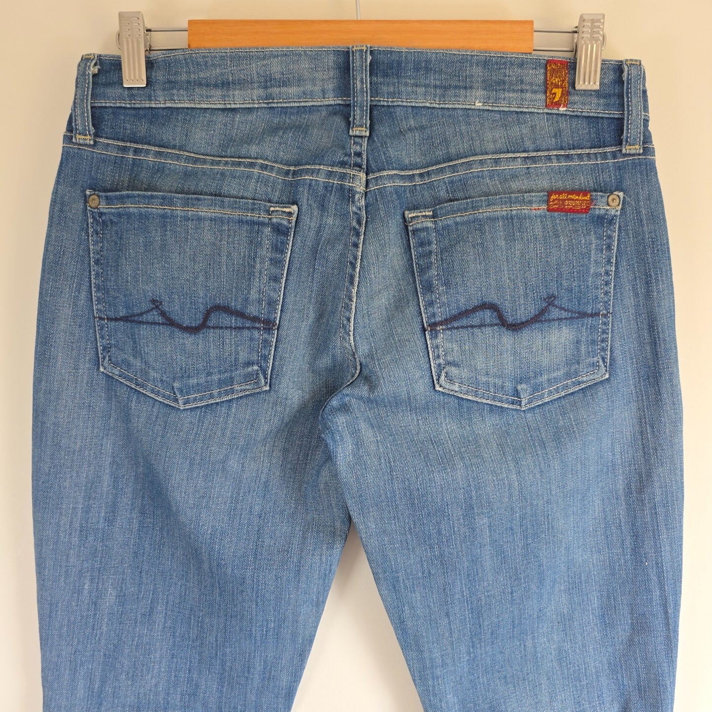 7 For All Mankind blue straight jeans with low rise and subtle branding details.