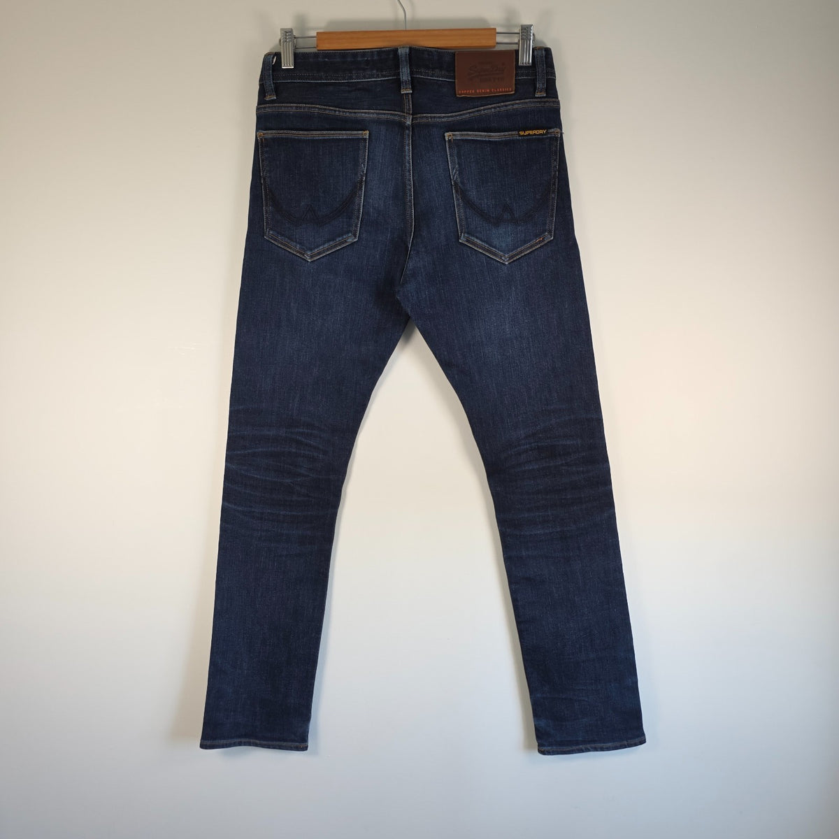 Superdry blue slim jeans with subtle fading, contrast orange stitching, and five-pocket design.