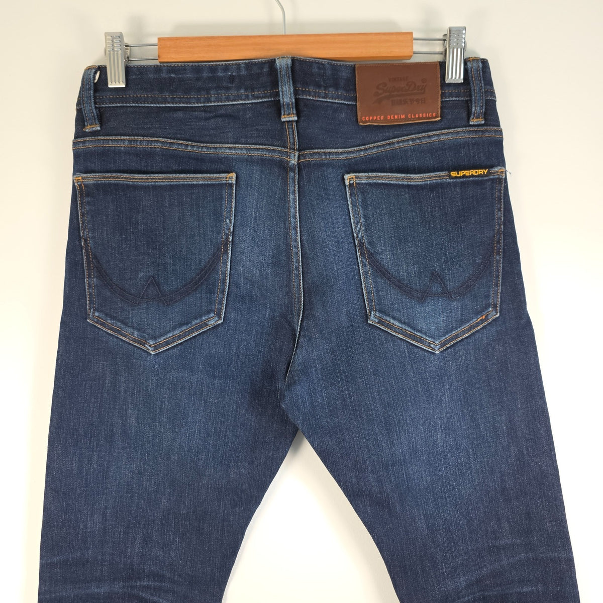 Superdry blue slim jeans with subtle fading, contrast orange stitching, and five-pocket design.