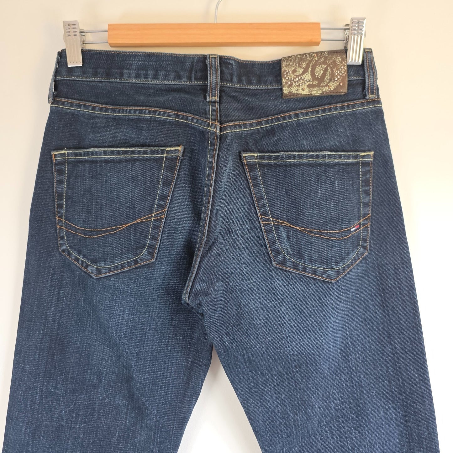 Tommy Hilfiger blue bootcut jeans with logo patch and classic denim texture.