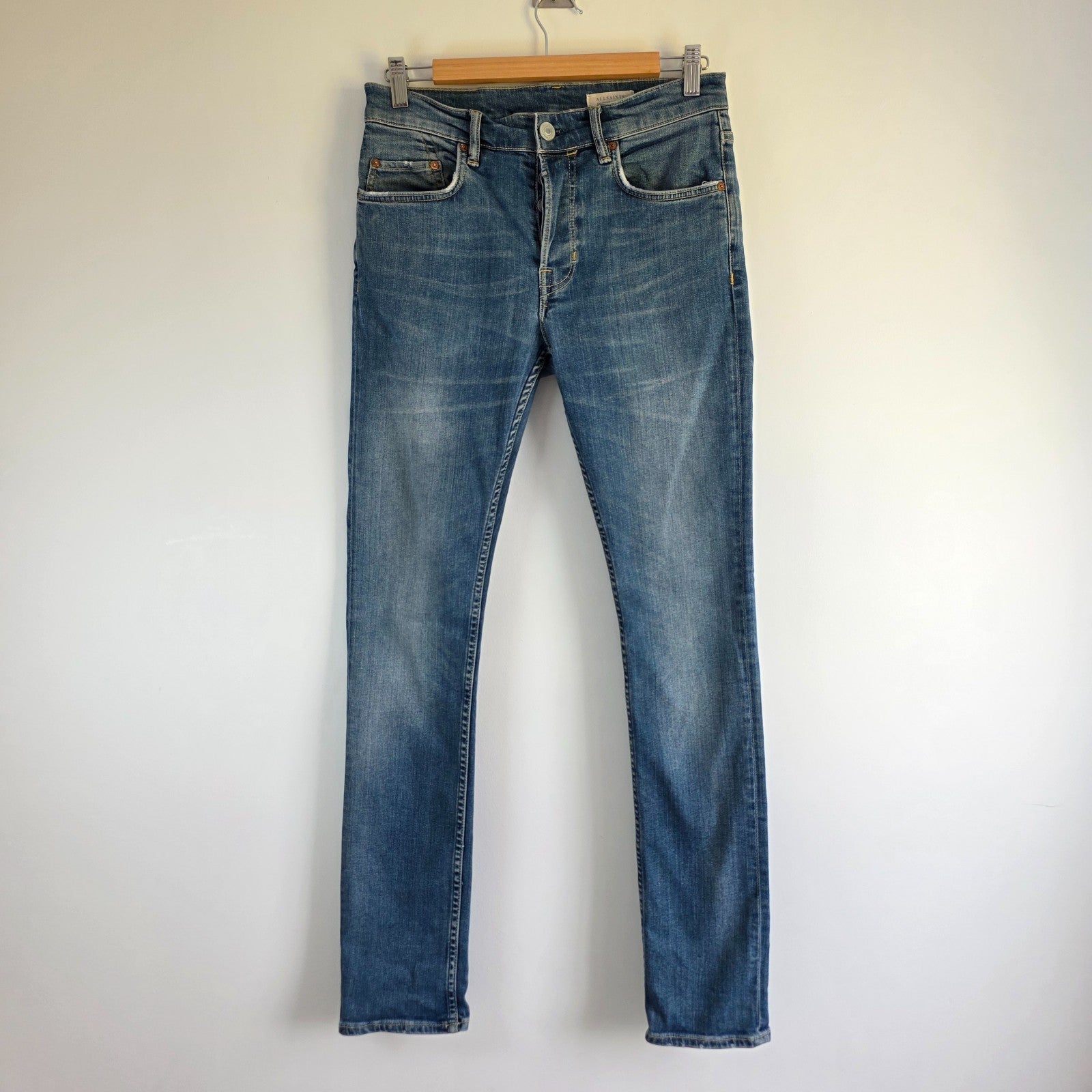 AllSaints blue skinny jeans with faded wash and modern slim fit design.
