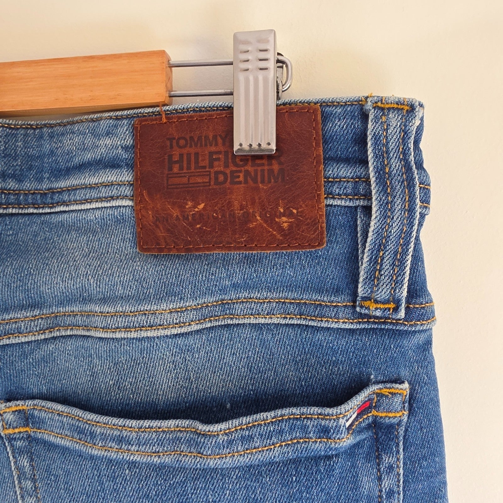 Tommy Hilfiger blue tapered jeans with stretch denim and small rip detail.