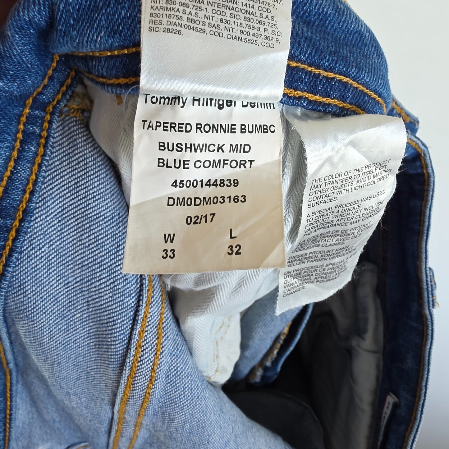 Tommy Hilfiger blue tapered jeans with stretch denim and small rip detail.