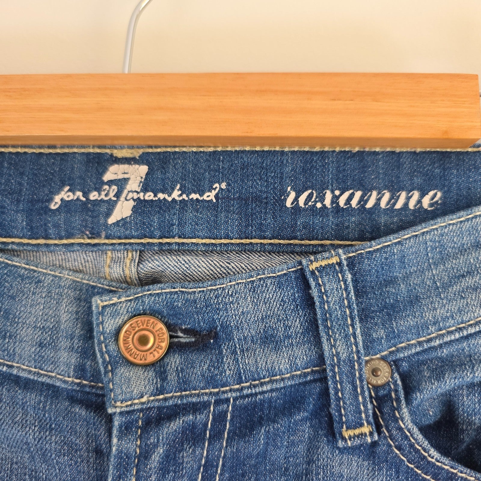 7 For All Mankind blue straight jeans with low rise and subtle branding details.