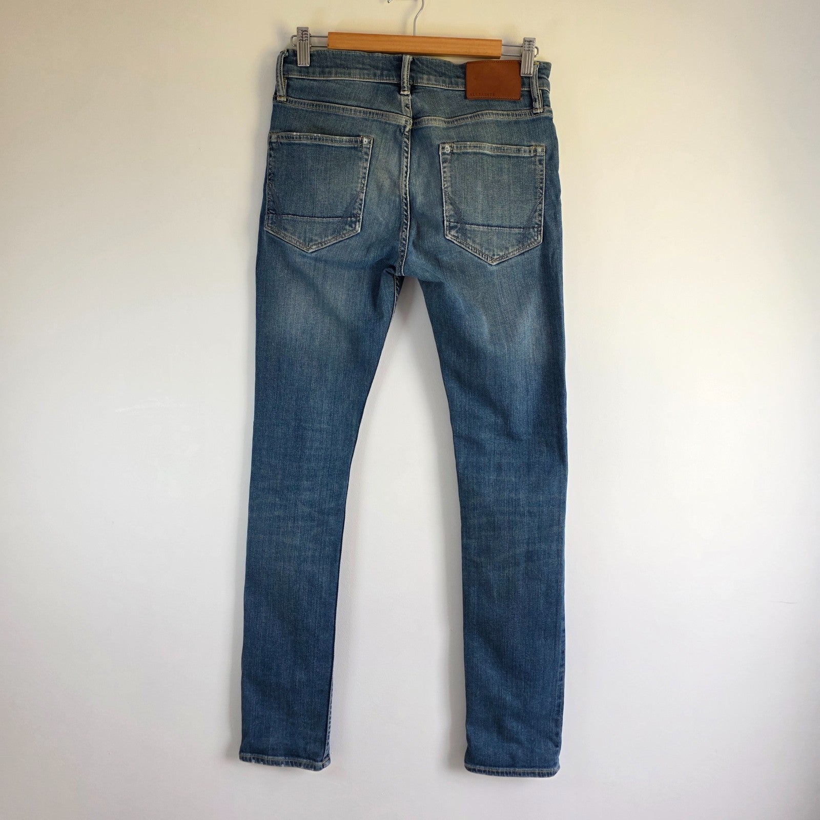 AllSaints blue skinny jeans with faded wash and modern slim fit design.