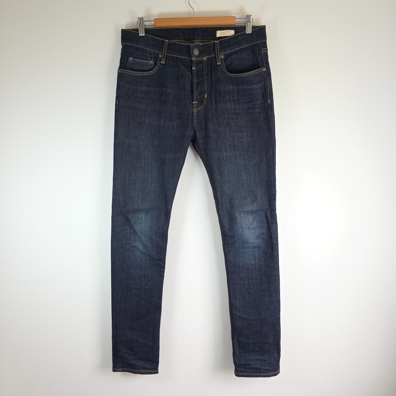 AllSaints blue skinny jeans with button fly and subtle logo detail.
