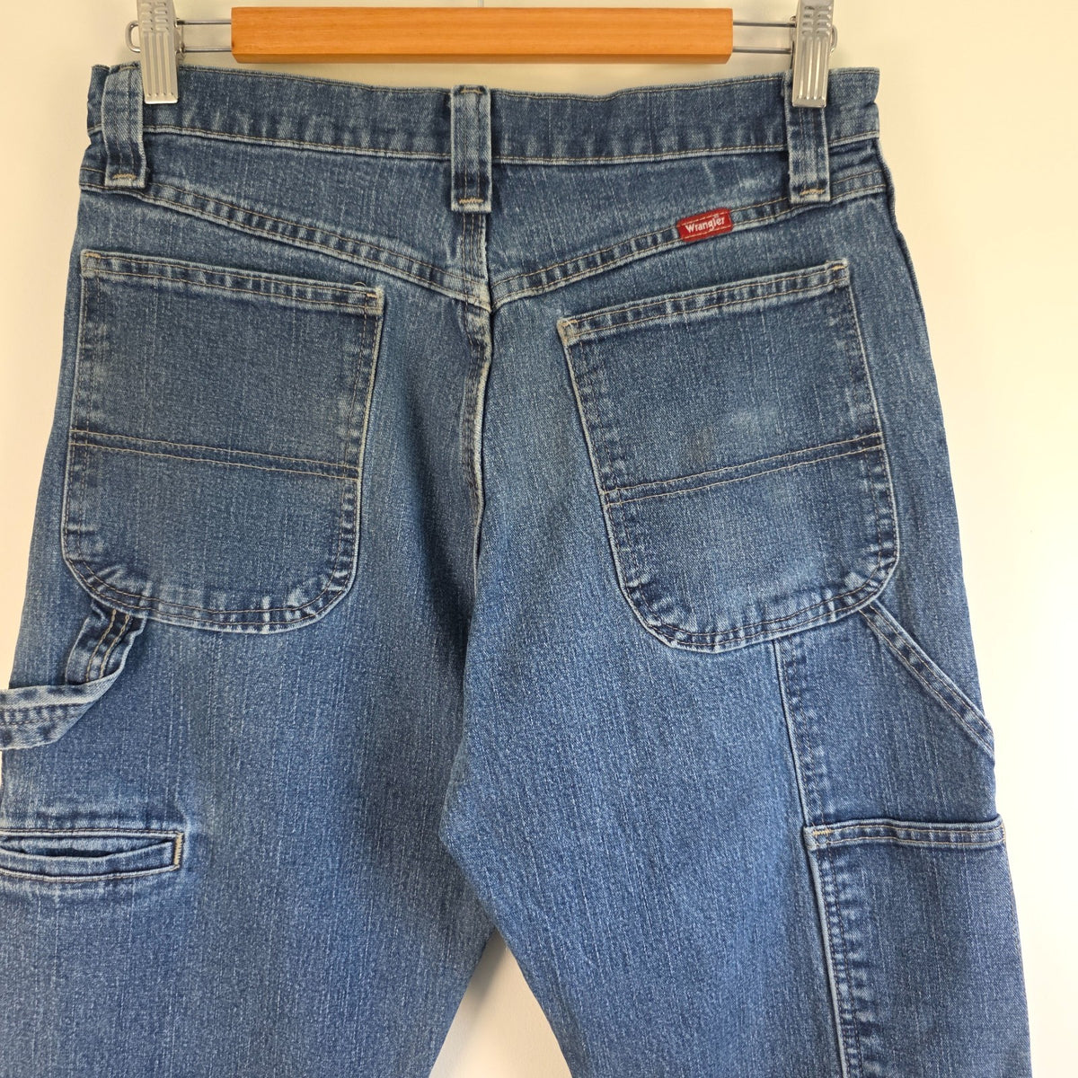 Wrangler blue carpenter jeans with distressed detailing, utility pockets, and hammer loop.