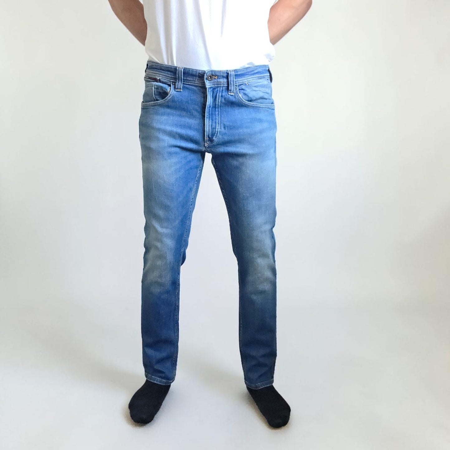 Tommy Hilfiger blue tapered jeans with stretch denim and small rip detail.