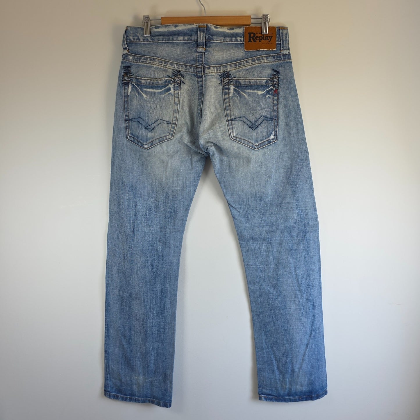 Replay blue straight jeans with button fly and light distressed pocket detailing.