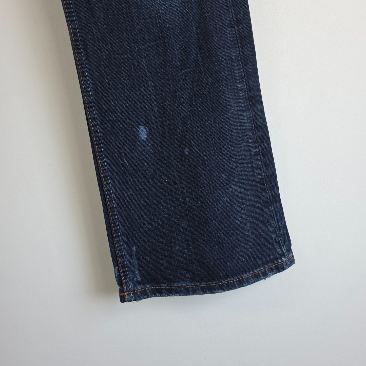 Tommy Hilfiger blue bootcut jeans with logo patch and classic denim texture.