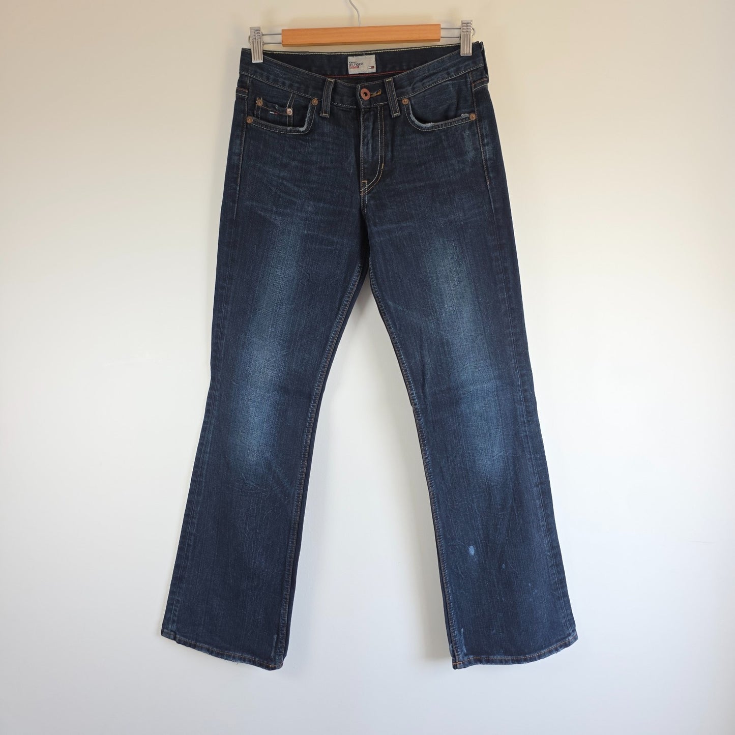 Tommy Hilfiger blue bootcut jeans with logo patch and classic denim texture.