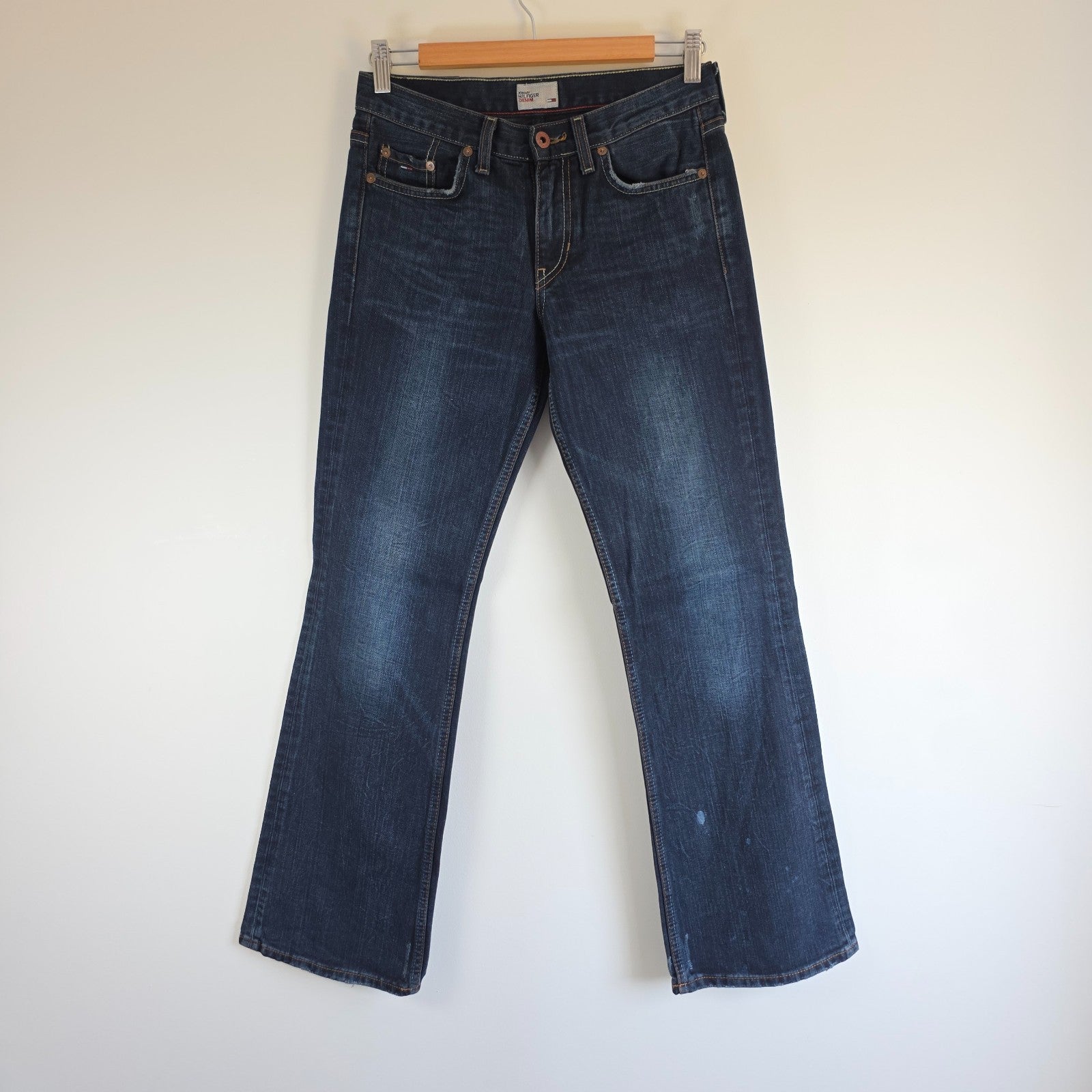 Tommy Hilfiger blue bootcut jeans with logo patch and classic denim texture.
