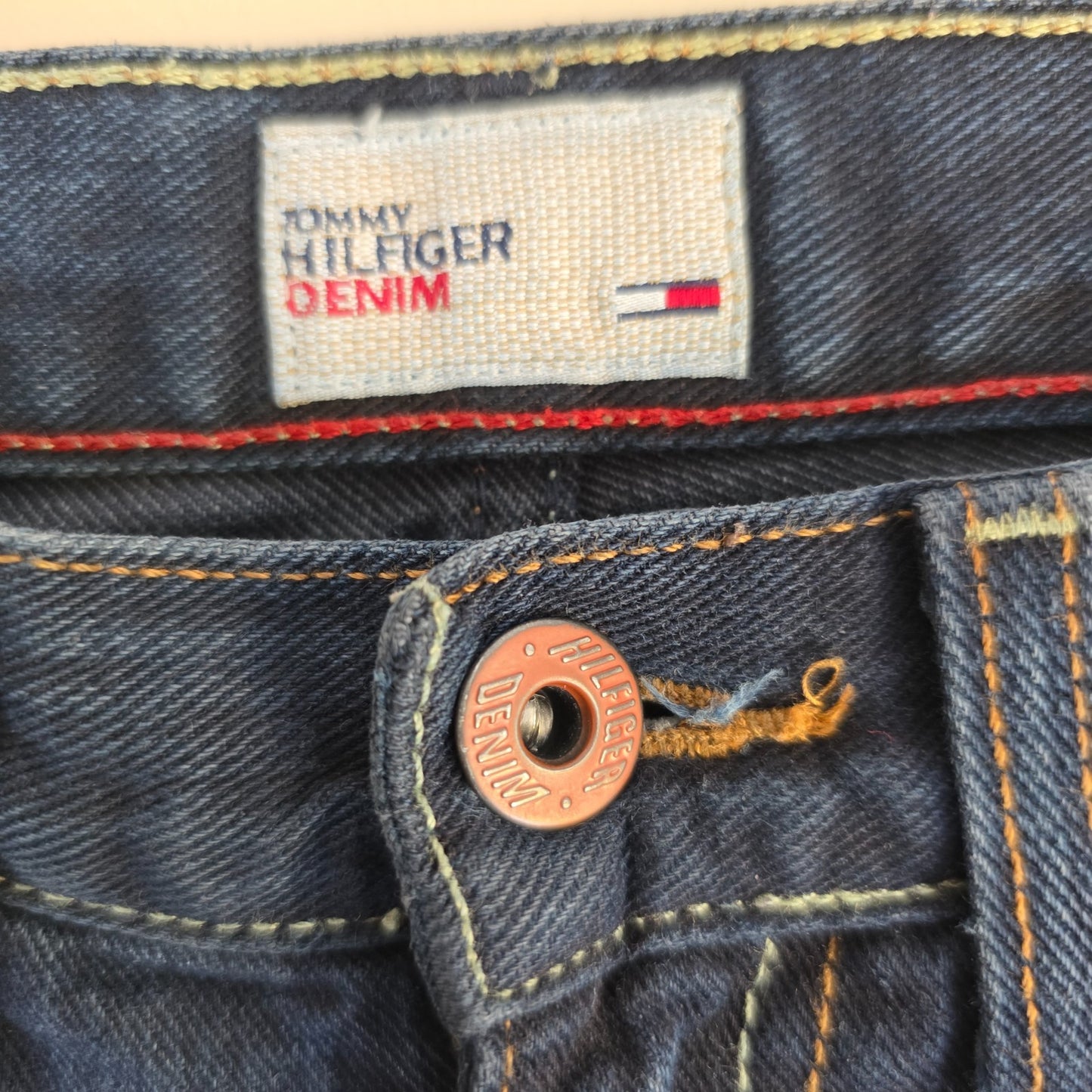 Tommy Hilfiger blue bootcut jeans with logo patch and classic denim texture.
