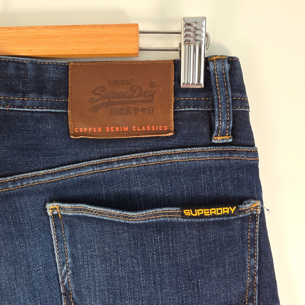 Superdry blue slim jeans with subtle fading, contrast orange stitching, and five-pocket design.