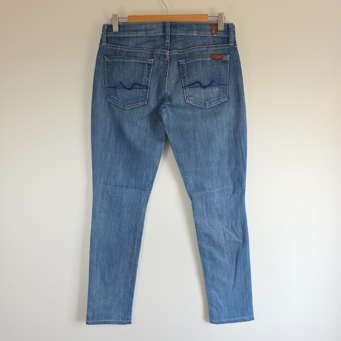 7 For All Mankind blue straight jeans with low rise and subtle branding details.
