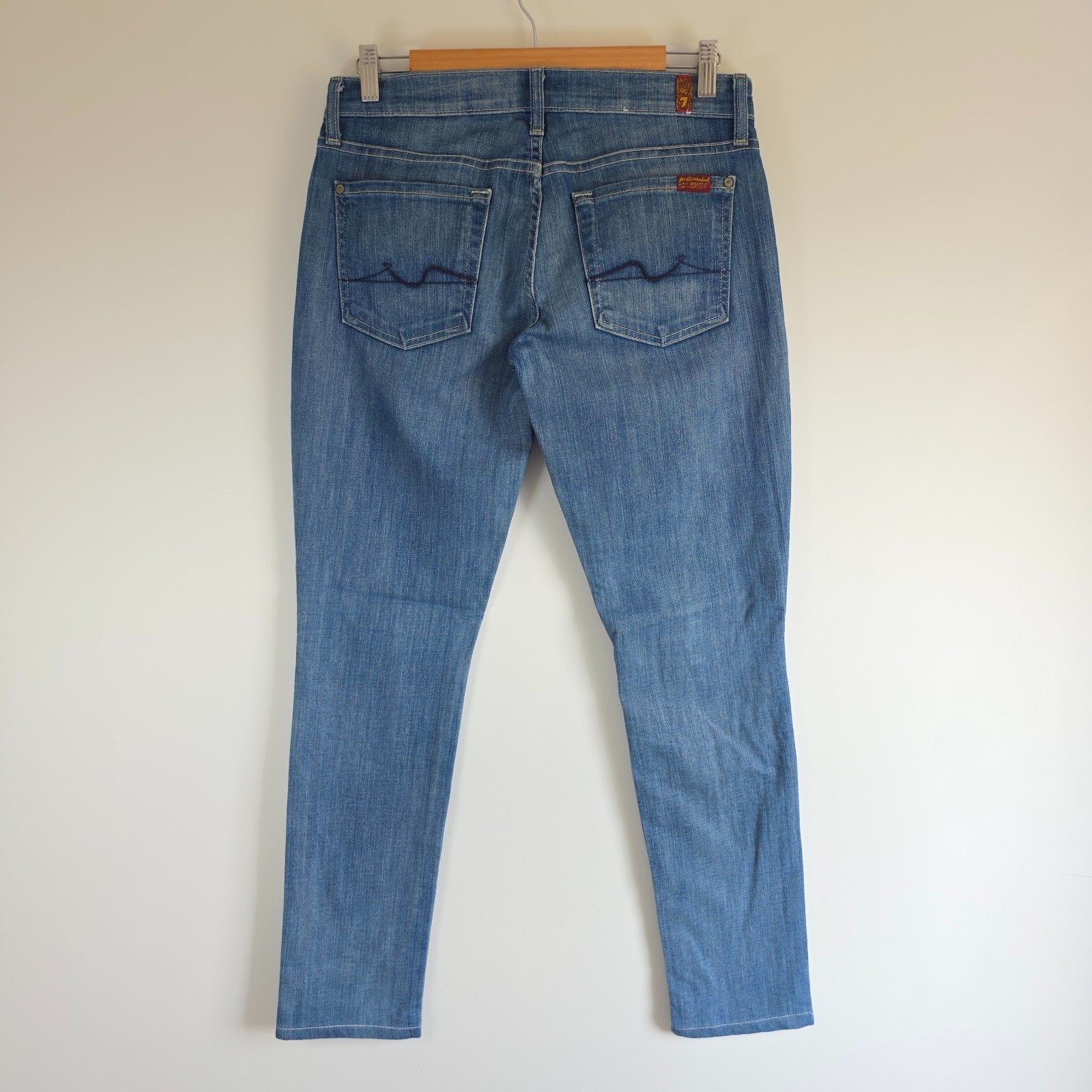 7 For All Mankind blue straight jeans with low rise and subtle branding details.