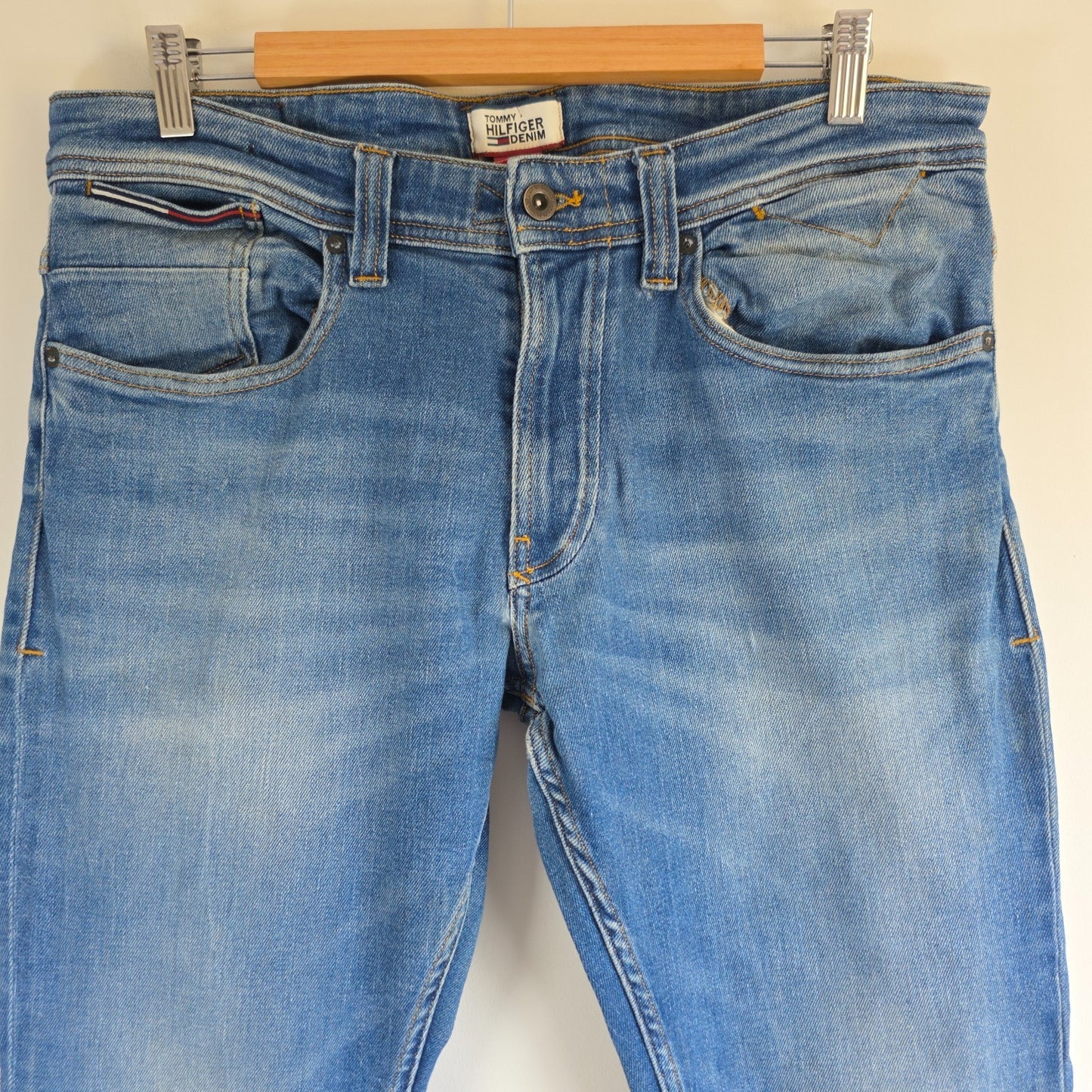 Tommy Hilfiger blue tapered jeans with stretch denim and small rip detail.