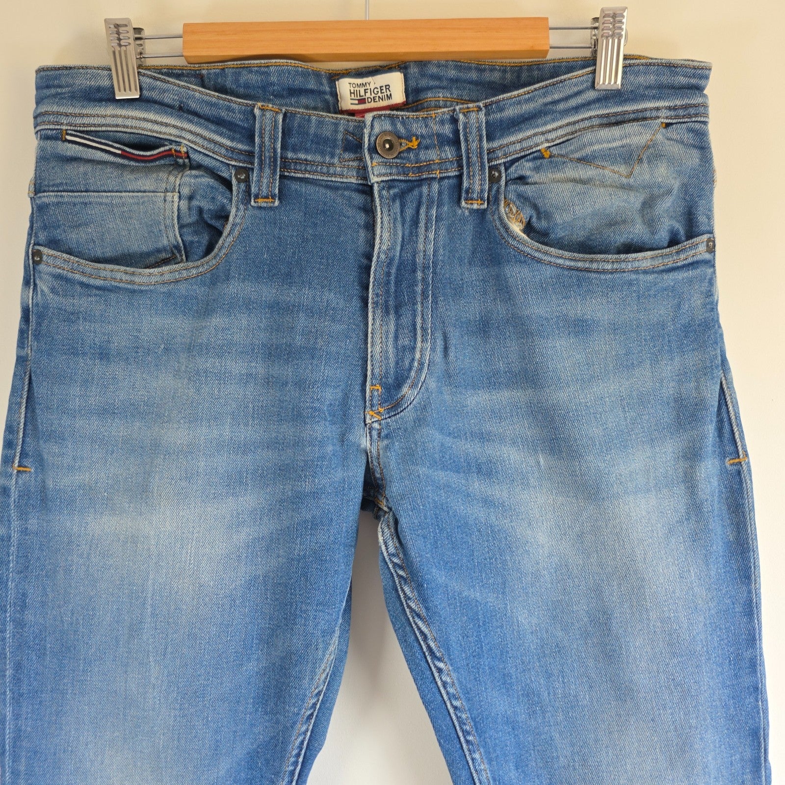 Tommy Hilfiger blue tapered jeans with stretch denim and small rip detail.