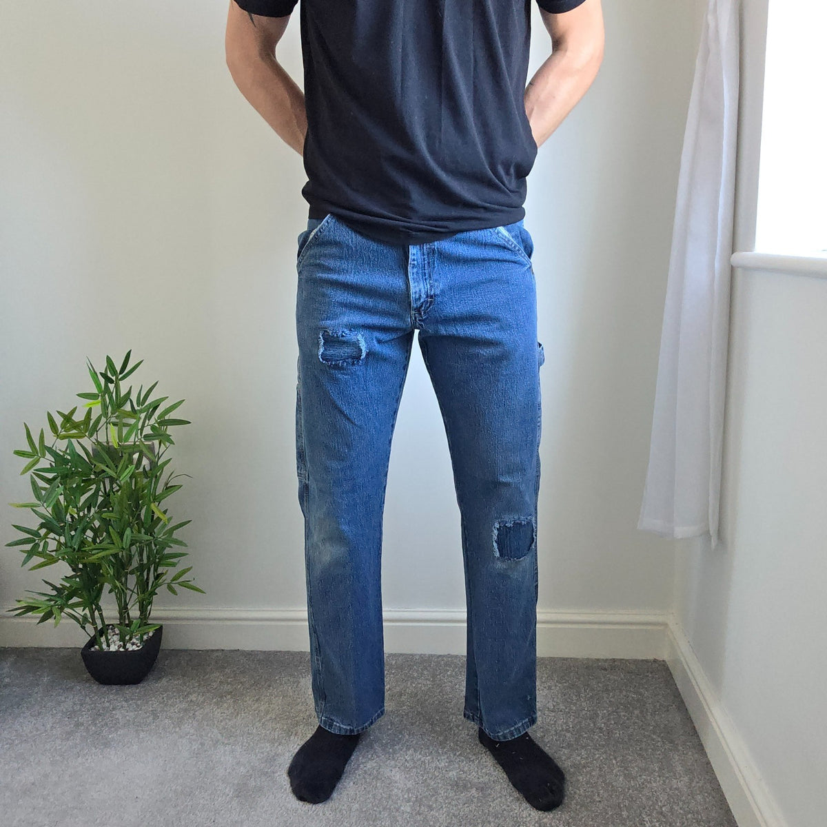 Wrangler blue carpenter jeans with distressed detailing, utility pockets, and hammer loop.